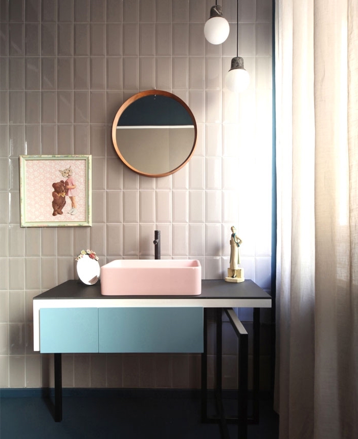 comment intégrer les couleurs pastel dans la salle de bain moderne avec miroir rond de bois et armoires en rose noir et bleu