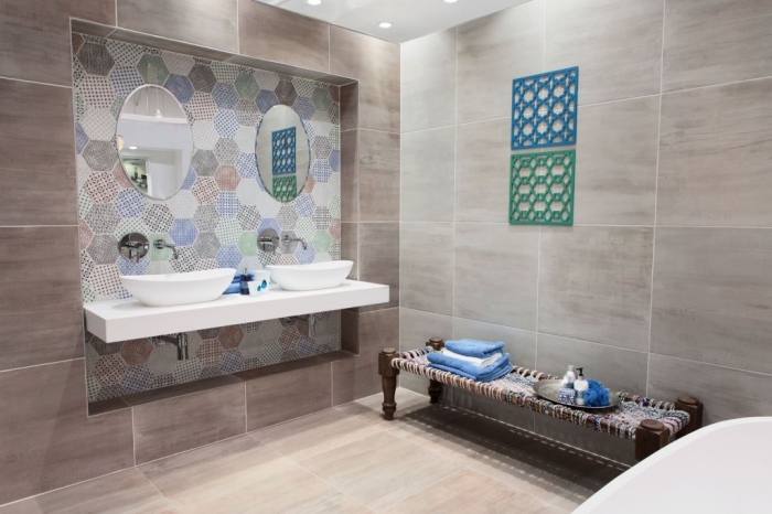 modele salle de bain au carrelage beige avec coin lavabo à design couleurs pastel et miroir oval, baignoire autonome blanche