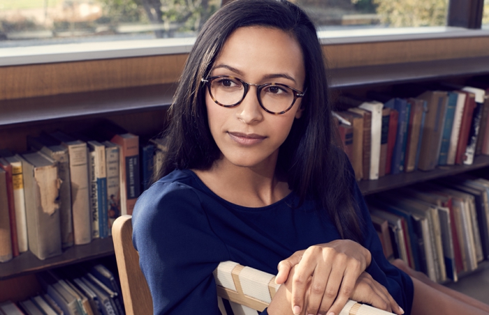 lunette carre, comment choisir ses lunettes, monture en noir et en marron clair, femme dans une bibliothèque, parmi les étagères de livres 