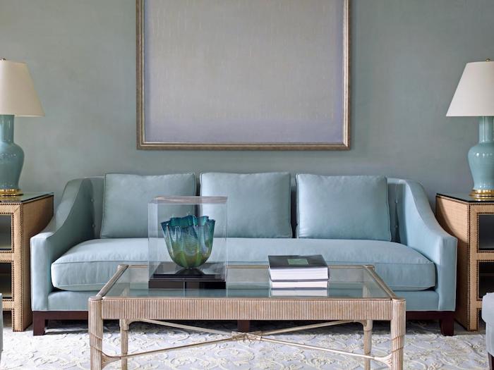 mur nuance gris tirant vers le bleu, canapé bleu, table basse en bois avec plateau en verre, tapis blanc, tables d appoint marron