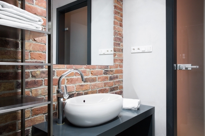 aménagement petit meuble salle de bain à espace limité aux murs en briques rouges avec meubles à design métallique et noir mate