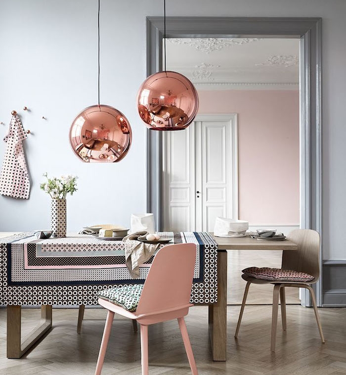mur peinture gris clair dans une salle à manger féminine, table et chaises en bois, chaise rose et suspensions boules rose gold