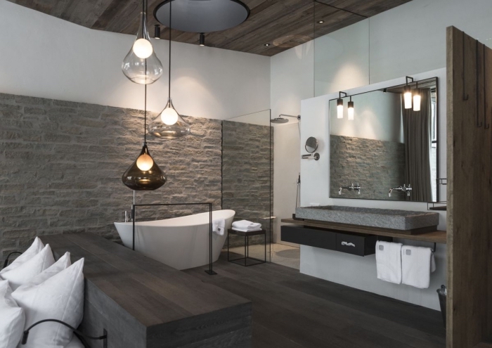 déco rustique et moderne dans une salle de bain au plancher de bois gris et mur en pierre et peinture blanche