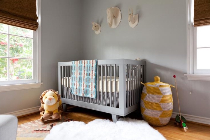 chambre complete bebe aux murs gris avec plancher de bois couvert de tapis moelleux blanc et jouets