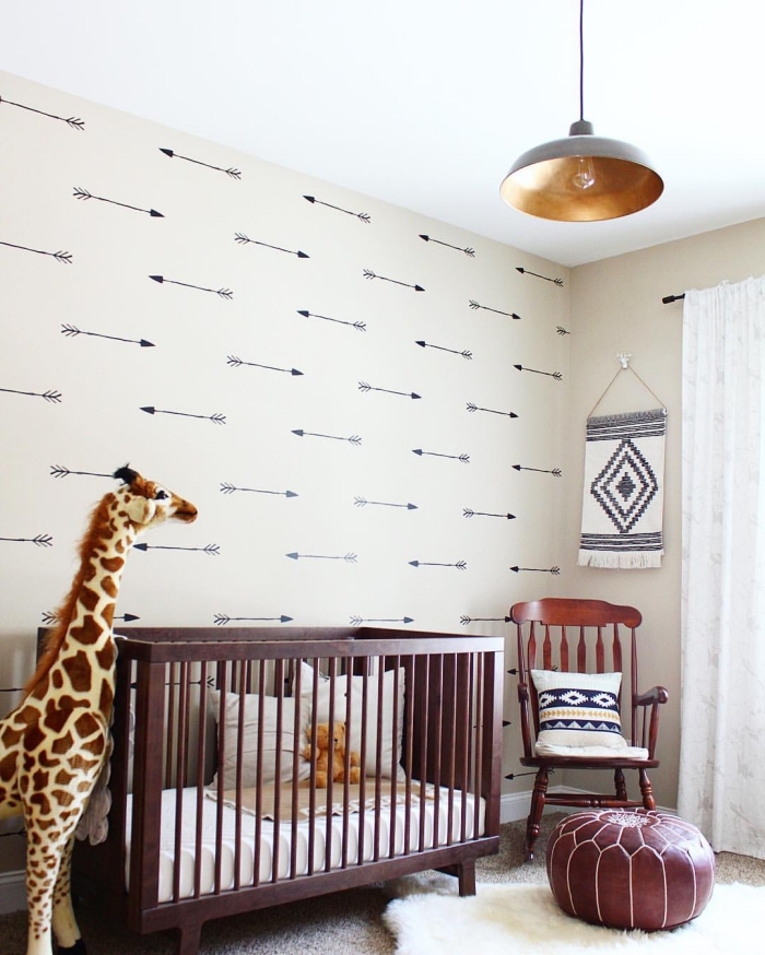 deco chambre bébé aux murs beige et plafond blanc avec meubles de couleur foncé et un grand girafe en péluche