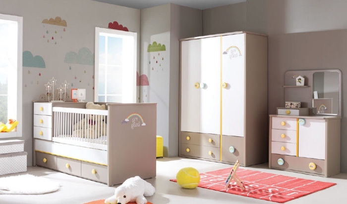 meubles blanc et beige dans la chambre bébé fille avec décoration à dessins nuages sur les murs et plusieurs jouets animaux