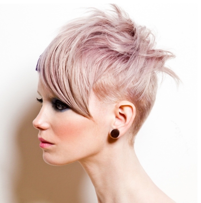 coloration moderne sur cheveux courts rasés sur le nuque et avec frange longue de côté, mèches rose pastel sur cheveux blonds