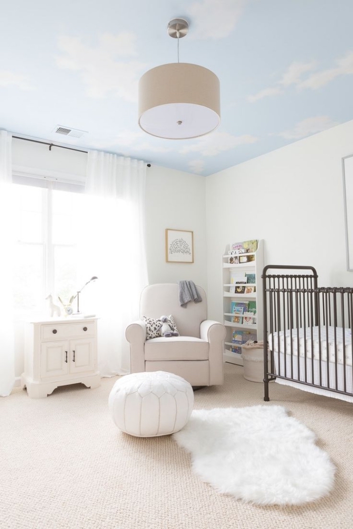 chambre bebe blanche au plafond à design ciel, accessoires cocooning sur tapis beige avec pouf et tapis blancs