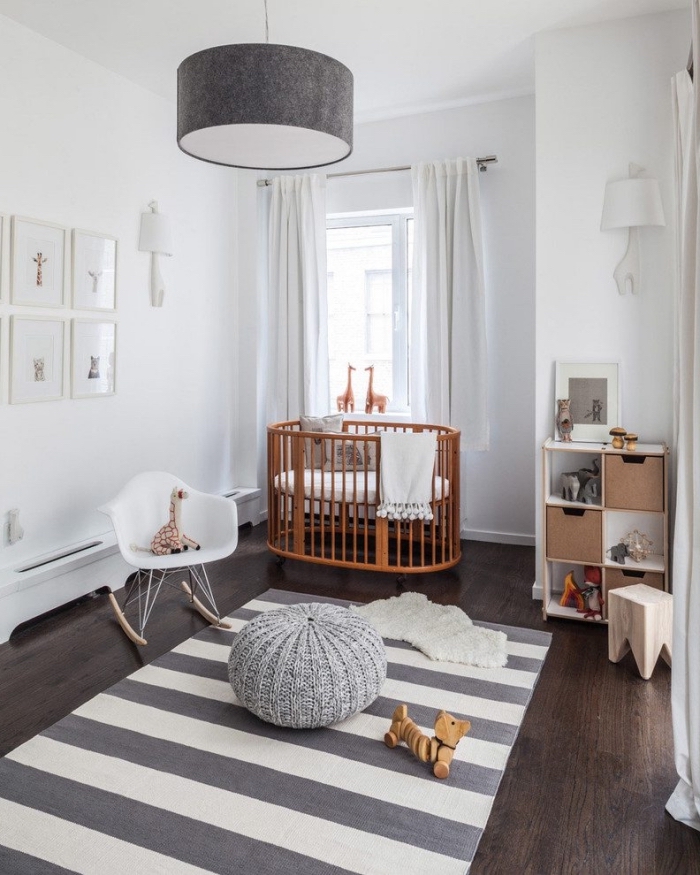 ambiance scandinave dans la chambre avec lit bebe fille rond, modèle de tapis rayé et pouf en crochet gris
