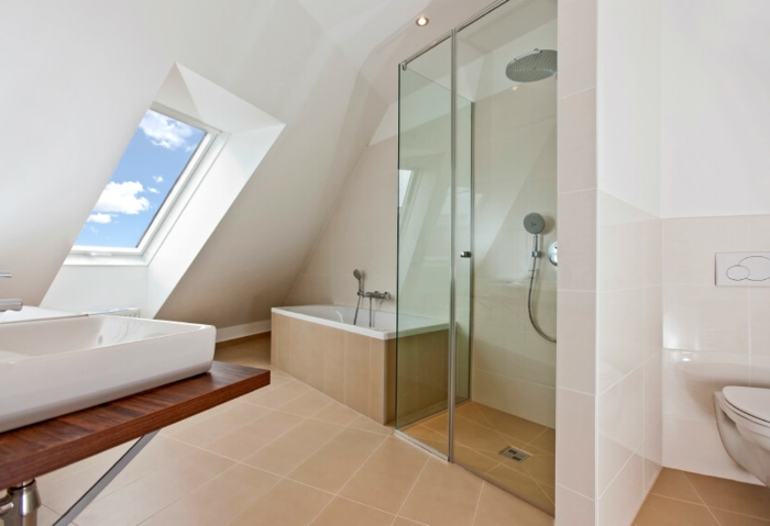 jolie salle d'eau mansardée, fenêtre en pente, cabine de douche en verre, carrelage de sol beige