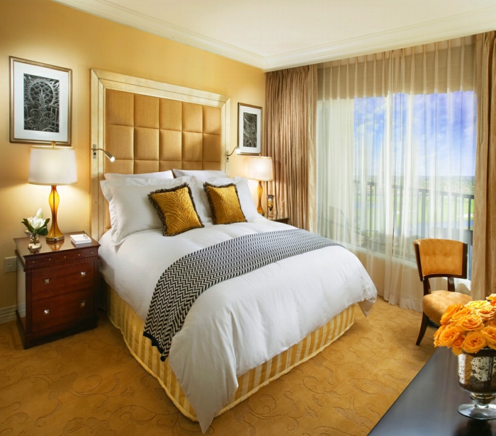 rideaux transparents, lit avec deux coussins jaunes ocre, tête de lit capionnée jaune