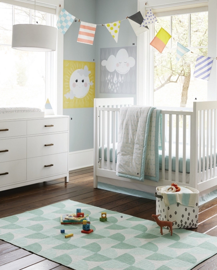 objets diy décoratifs dans la chambre bébé aux murs bleu pastel, meubles de bois peints en blanc sur un parquet de bois foncé