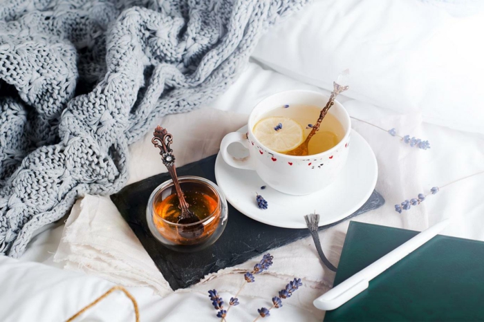 lit cocooning avec un plad tricoté, des tasses avec des boissons chaudes