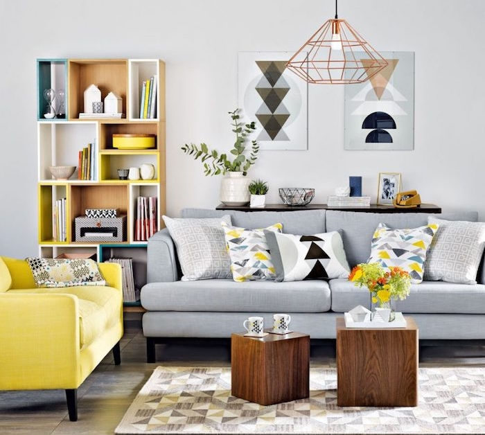 mur décoré de peinture gris clair, canapé gris, fauteuil jaune, tables basses en cube de bois, etagere rangement en bois, suspension originale