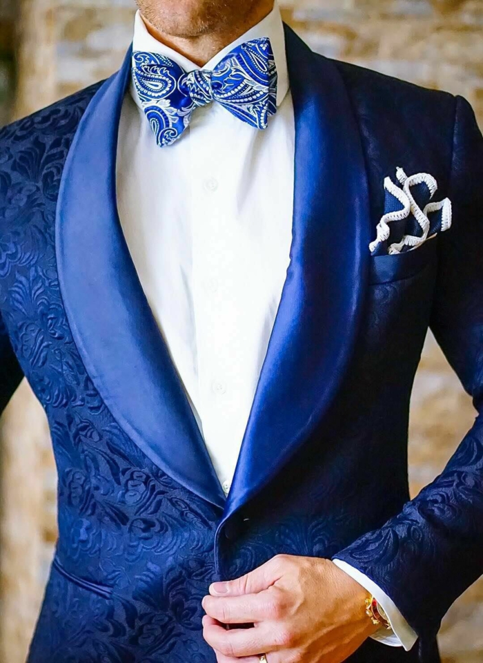 veste de costume homme, costume nœud papillon, bleu roi magnifique, mouchoir de poche en bleu roi et blanc, nœud papillon en bleu roi avec des accents en blanc, arabesques décoratives en finition satinée sur la veste, revers en satin bleu roi