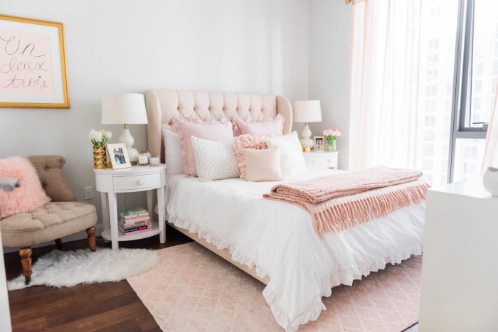 chambre à coucher blanche au parquet de bois foncé, grand tapis de couleur rose poudré et petit tapis à imitation peau animal blanc
