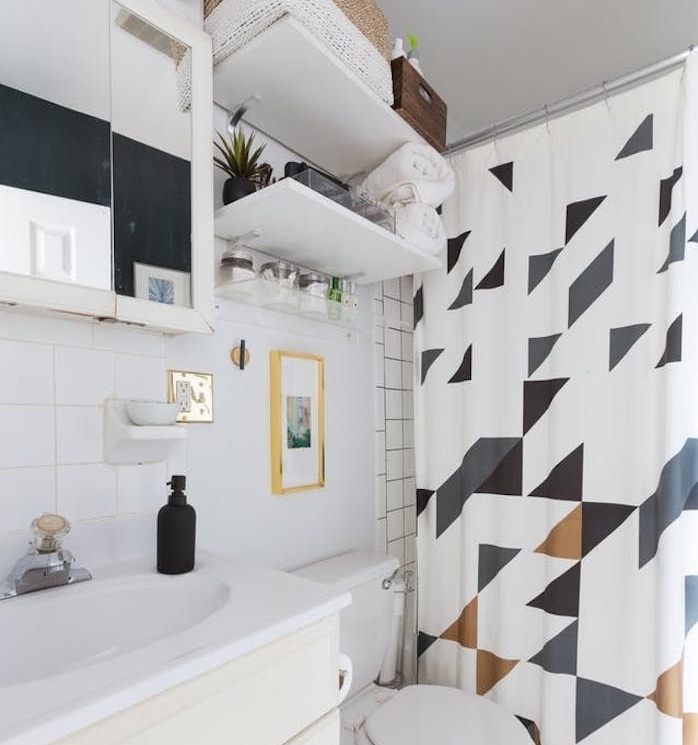 exemple petite salle de bain avec dea étagères au-dessus de toilette, rideau de douche à motifs géométriques, placard avec miroir intégré