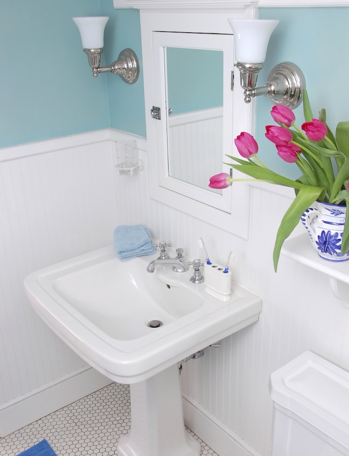 exemple de petite salle de bain design, lavabo console, miroir, peinture mur bleu, sol carrelage vintage, bouquet de tulipes