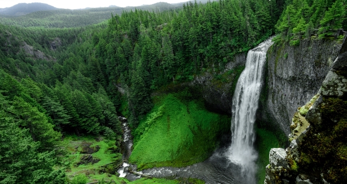 beau fond d écran avec chute d'eau et rivière dans une forêt verte d'arbres conifère et une vue vers les collines