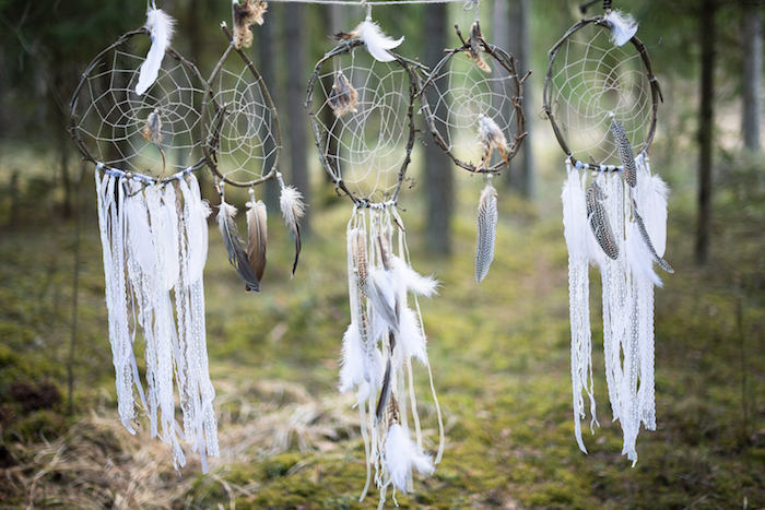 décoration extérieur forêt, attrape reve fabrication traditionnelle avec des cerceaux en branches naturelles, chutes de dentelle, plumes, filet blanc