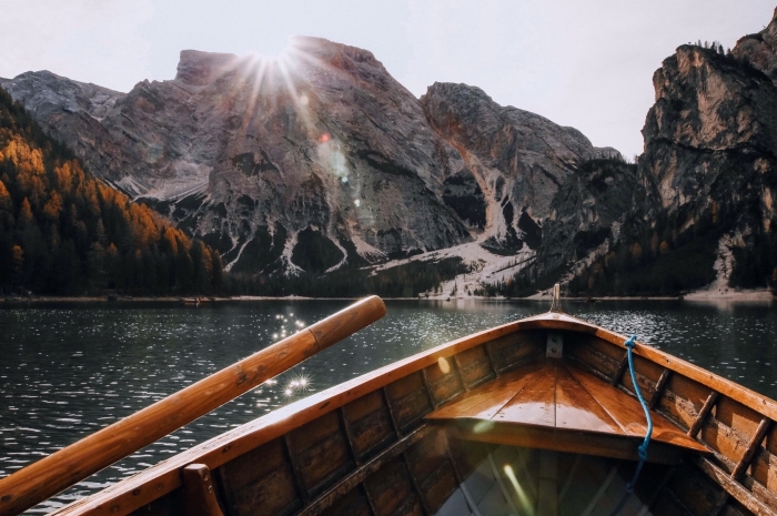 photo de bateau dans un lac au coeurs des montagnes, fond d écran jolie avec soleil au dessus des rochers