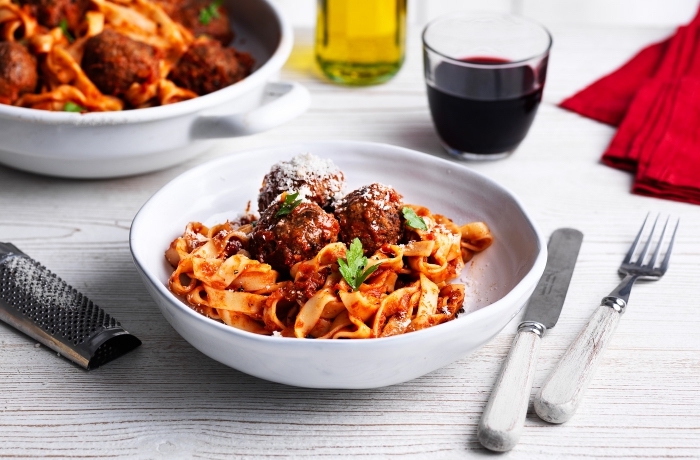idée repas convivial entre amis, spaghettis aux boules de viande hachée à la sauce tomate servis avec basilic et parmesan 