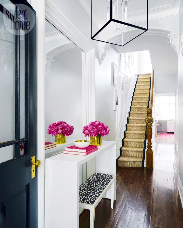 idée déco de couloir blanc avec porte noire et escalier en bois avec tapis doré et noir, meubles d'entrée en blanc