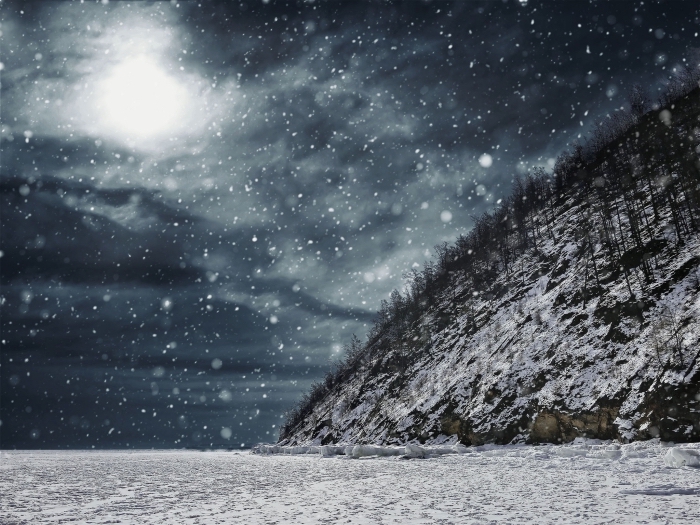 fond ecran paysage hivernal avec tempête de neige au-dessus des champs, colline enneigé et ciel gris et noir