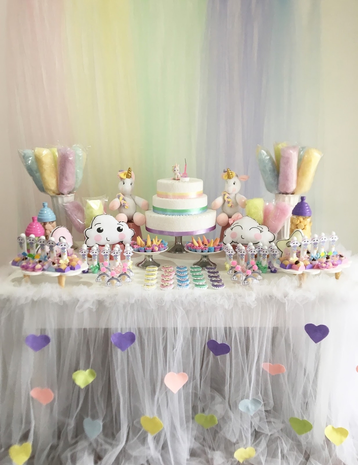 jolie déco de buffet de desserts revêtu d'une jupe de table en tulle personnalisée avec des coeurs en papier pour un anniversaire licorne à inspiration kawaii tout en délicatesse