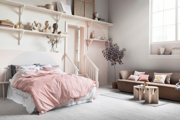 aménagement studio avec peinture rose pale et beige, rangement mural avec étagères de bois, modèle de canapé marron avec table basse