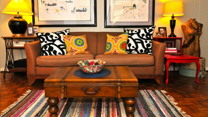 table basse valise vintage, sofa marron, chaise rouge baroque, deux chevets avec lampes abat-jour, tableaux peintures 