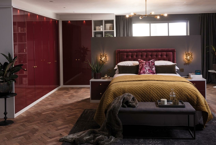 peinture murale rouge bordeaux, plaid de lit vert curry, banquette de lit grise, parquet chevron