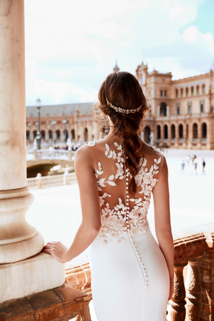 vision romantique avec coiffure en tresse et couronne, modèle de robe de mariée blanche à dos boutonné avec fleurs
