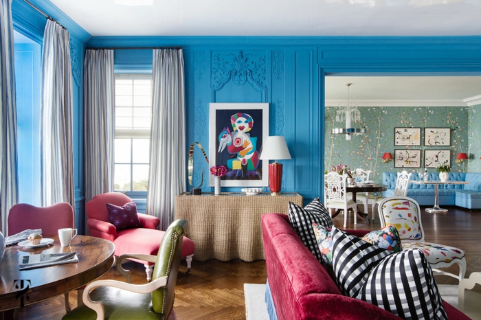 salle de séjour avec couleurs contrastantes, sofas rouges, chaises ancienne; table ovale, coussins motifs carrés