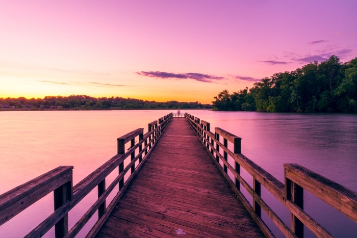pont de bois au-dessus d'un lac avec forêt d'arbre et ciel en couleurs rose et jaune illuminé par les rayons du soleil, wallpaper fond d écran lever du soleil