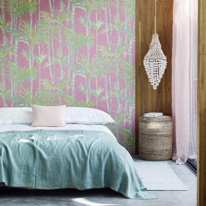 modèle de papier peint tropical en vert et rose dans une chambre à coucher aménagée avec un grand lit sur plancher de béton
