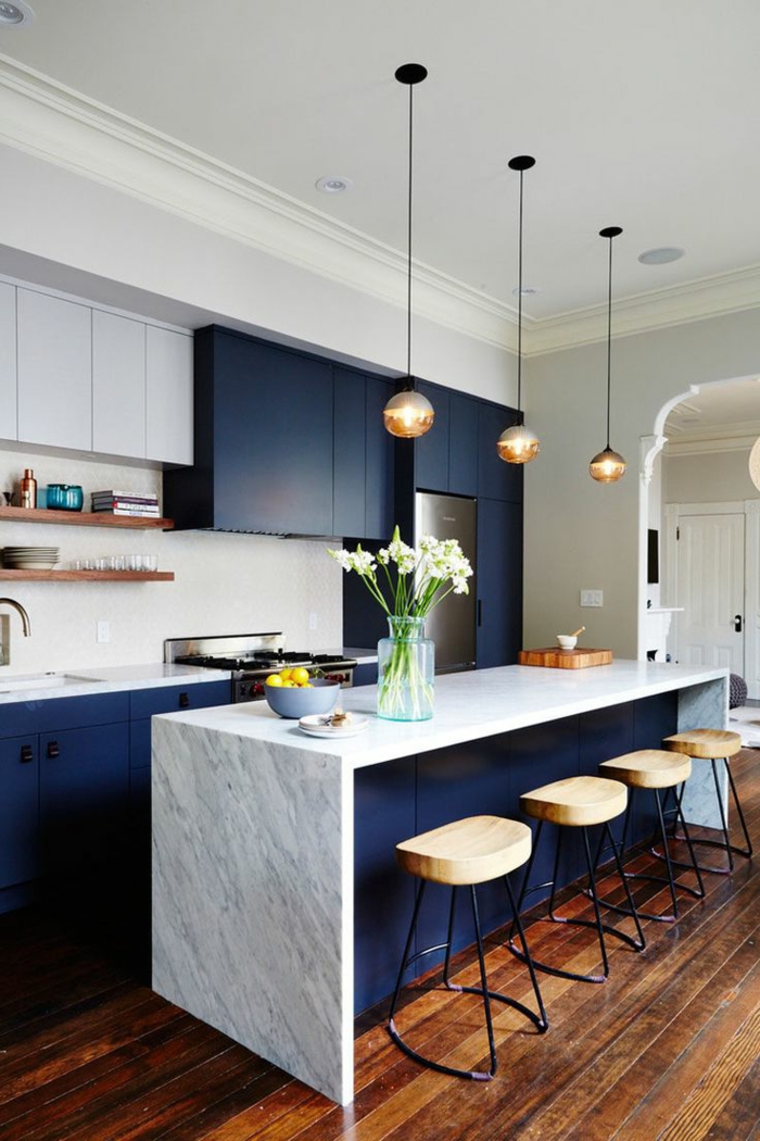 cuisine en blanc et bleu, petits tabourets de bois, sol en bois, mur avec rangement élégant