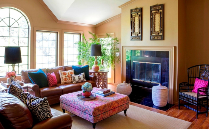 table pouf rose, tapis beige, sofas en cuir, murs en orange pâle, deco ethnique, cheminée murale