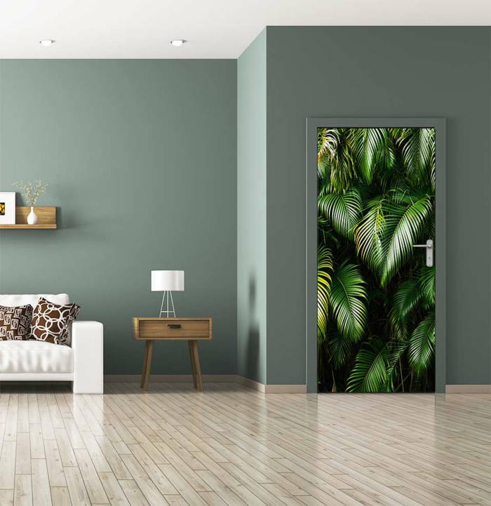 amenagement salon, porte avec sticker mural aux motifs flore dans la jungle, feuilles de palmiers, murs n vert pistache, parquet en gris, canapé blanc