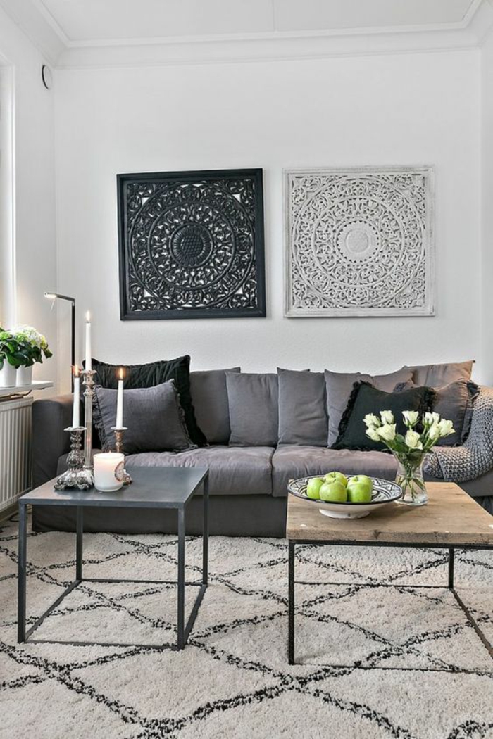 deco epuree, murs en blanc, tapis aux losanges noirs sur fond couleur crème, deux panneaux en métal blanc et noir avec des motifs arabesques orientaux et zen, canapé en gris
