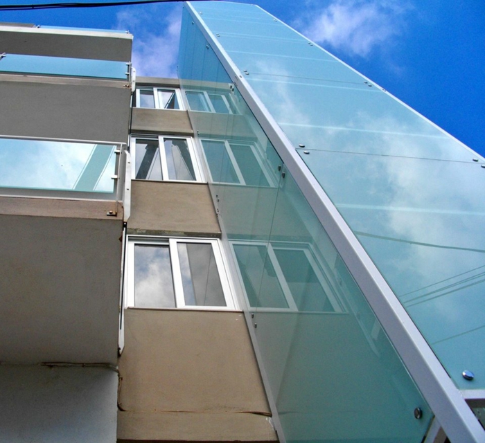 decoupe verre, édifice avec colonne en verre, murs couleur taupe, verres aux effets miroitants, fenêtres aux cadres blancs