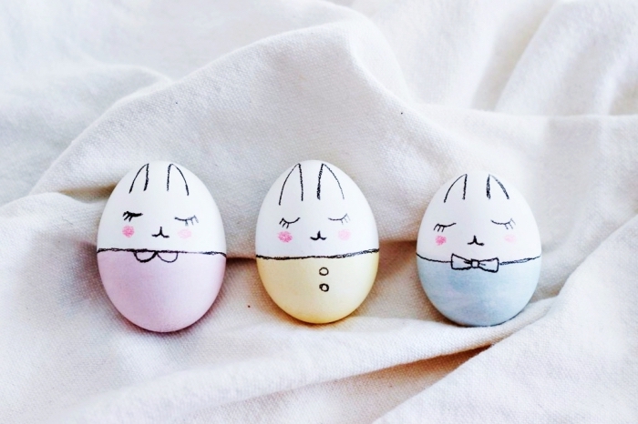 modèles d'oeufs décorés à design lapin de paques, coquilles blanches bicolore avec visages dessinés en marqueur noir