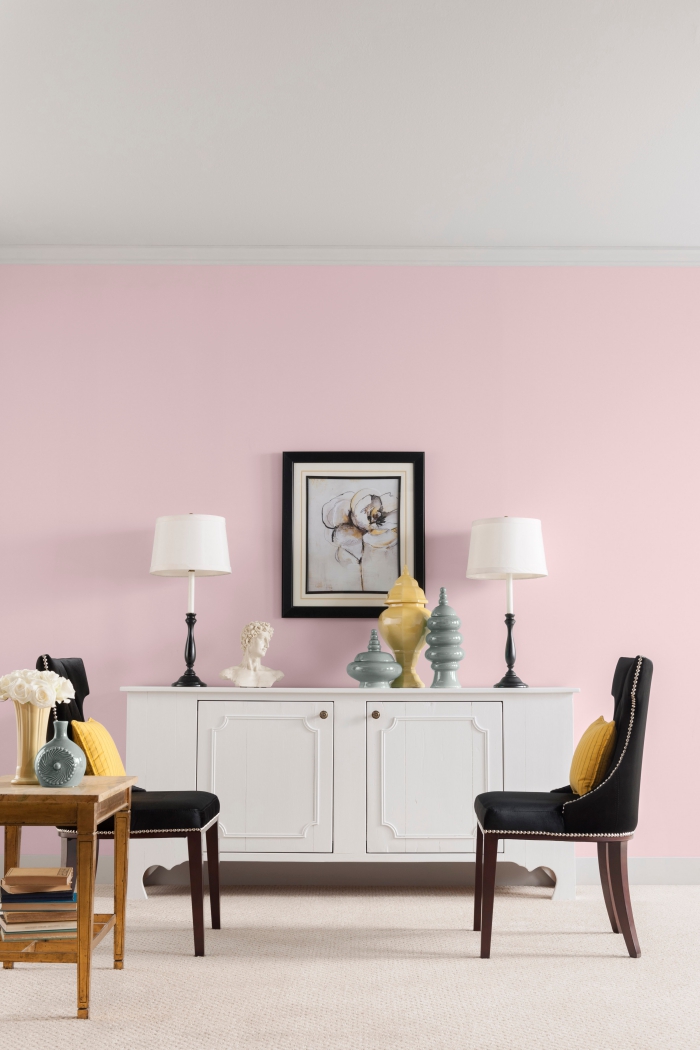 aménagement salon aux murs de peinture rose poudré avec plafond blanc et grand tapis beige, armoire blanche avec poignées dorées