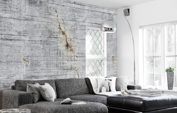 salon blanc et gris avec peinture murale blanche et déco de mur en papier peint à design béton, modèle de canapé d'angle gris combiné avec table de cuir noir