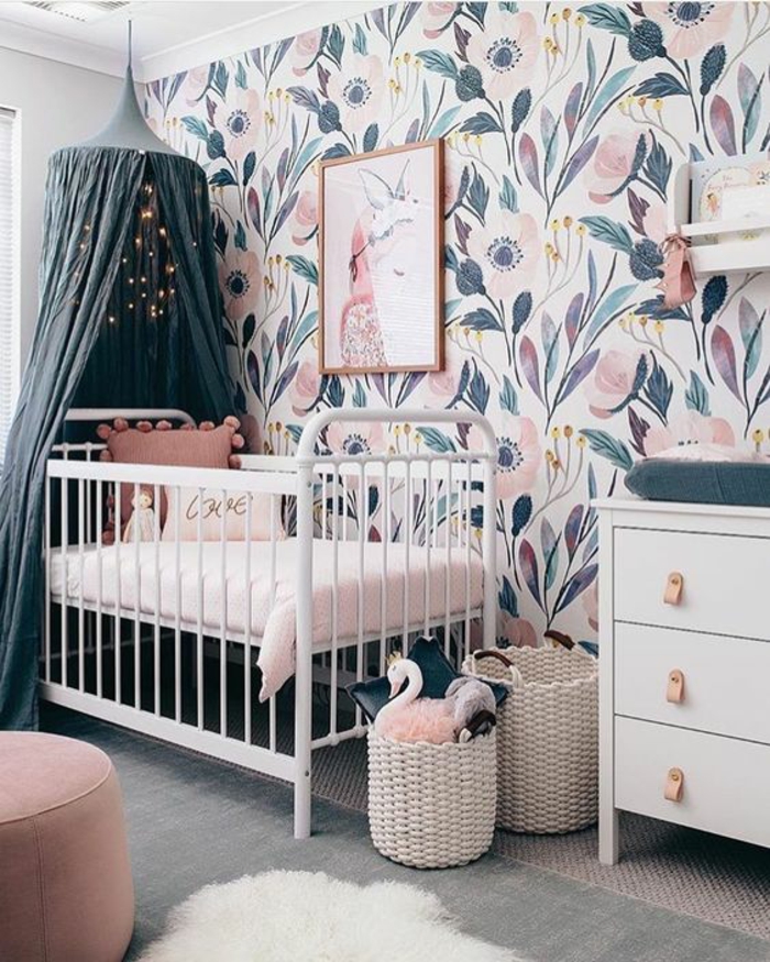 cadre chambre bébé, chambre rose et gris, meuble en bleu pastel, mur avec des grandes fleurs en bleu canard et rose, moustiquaire en bleu pétrole, tabouret rond en rose poudré