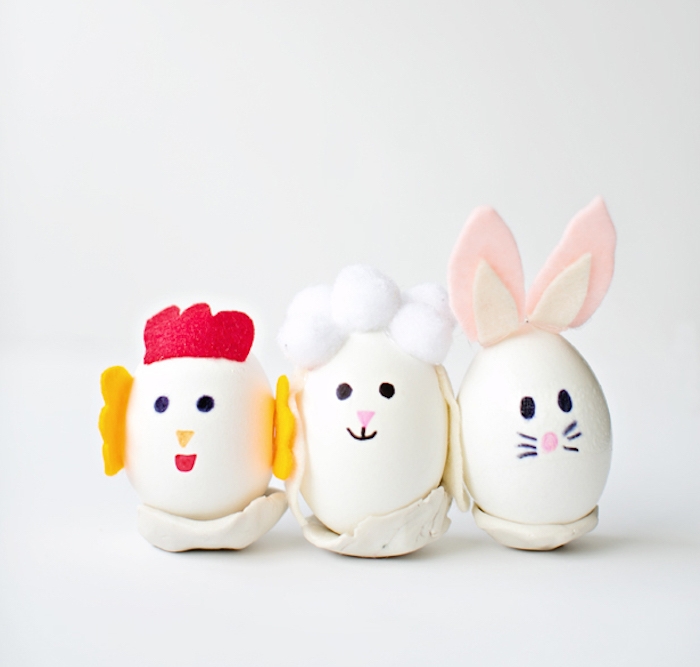décoration oeuf de paques blanc à motif lapin de paques, brebis et poussin en feutrine coloré et dessin de traits de figure au feutre
