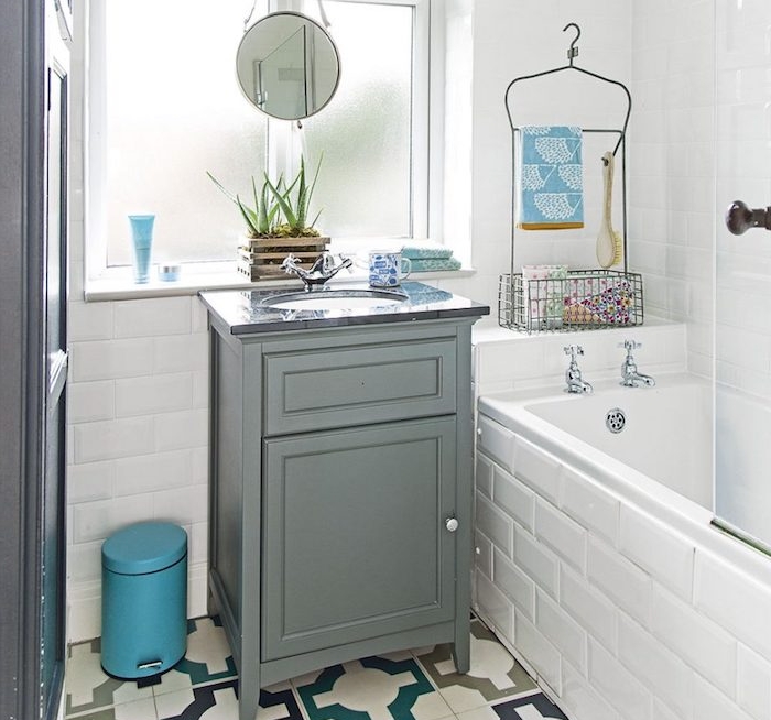 exemple de petite salle de bain avec baignoire à encastrer, meuble gris, carrelage mur blanc et carrelage sol à motifs retro, petit miroir rond