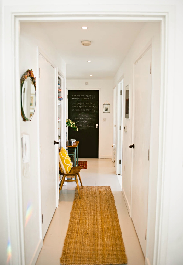aménagement couloir en blanc avec tapis beige et porte en peinture ardoise, décoration avec coussin jaune et miroir rond