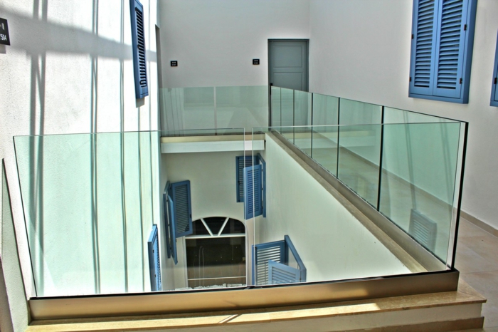 escalier arty dans un édifice public, volets en bleu indigo, garde-corps en verre transparent, carrelage couleur ivoire