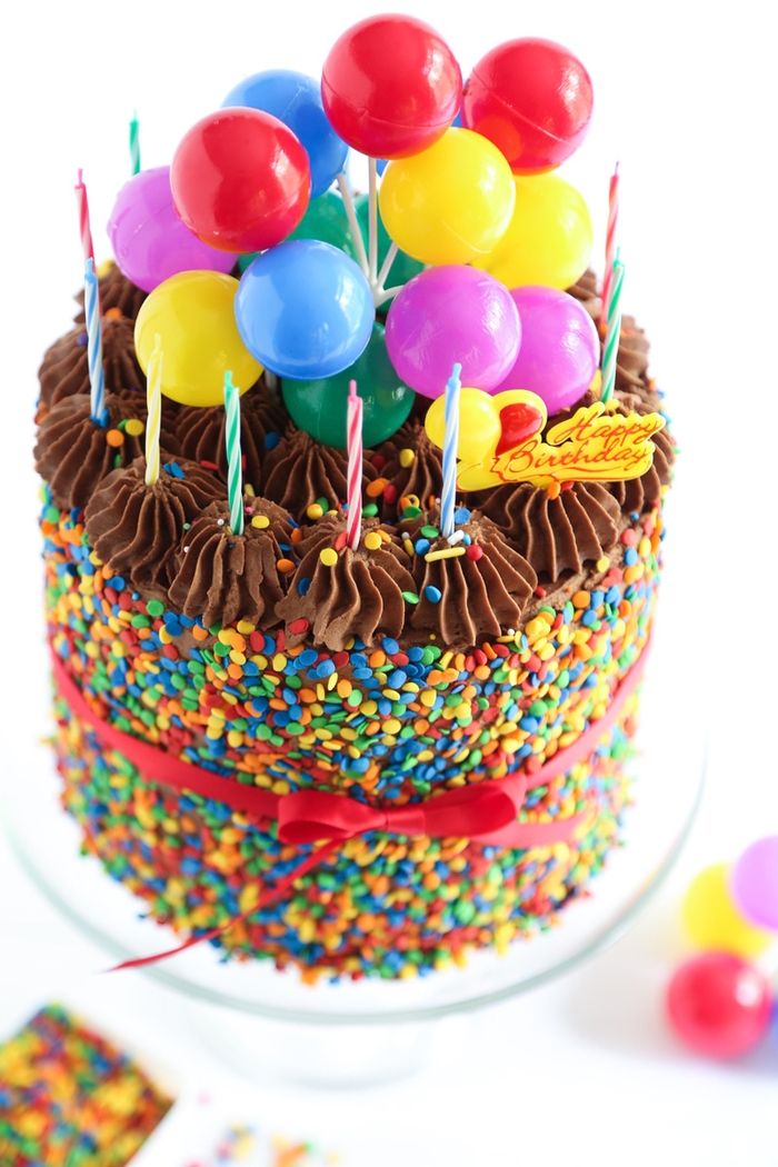 recette de gateau d'anniversaire facile au chocolat avec bougies multicolores et confettis décoré de mini-ballons et d'un joli ruban rouge
